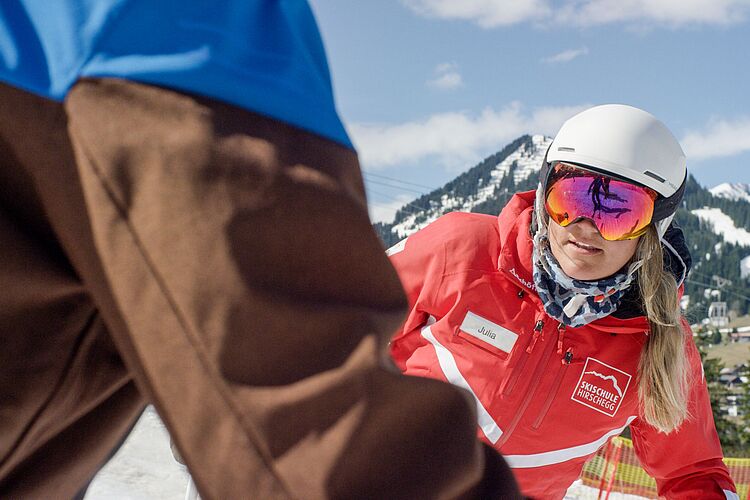 Skilehrerin zeigt die richtige Technik auf der Piste 